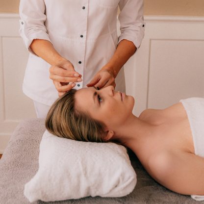 Woman receiving acupuncture treatment on head.